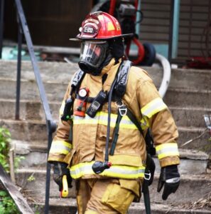 Firefighters walks away from fire scene with protective mask on