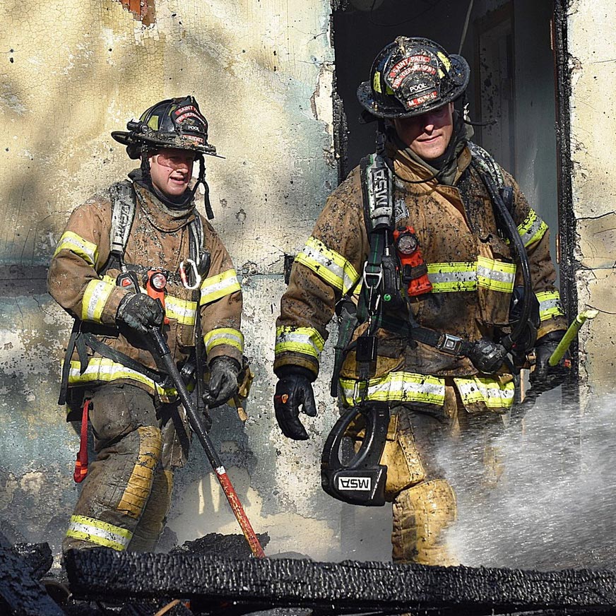 Two firefighters outside burned building